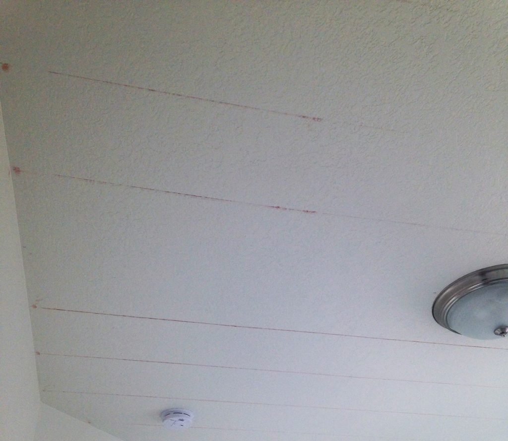 Paint stripes on a ceiing, first mark lines with a chalk line tool, red chalk lines on the white painted ceiling.