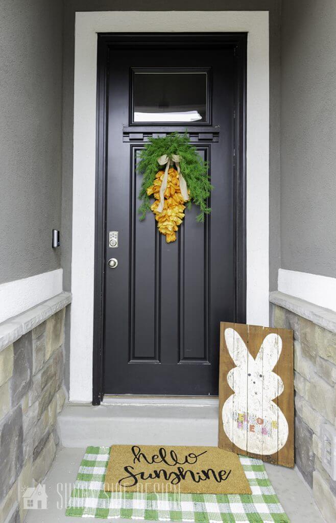 Front porch decorated with tulip carrot wreath and a bunny pallet sign.