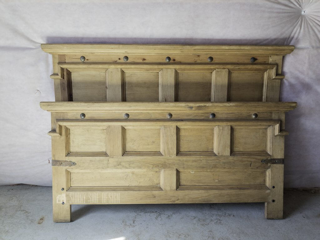 Rustic yellow pine headboard and footboard against unfinished basement wall.