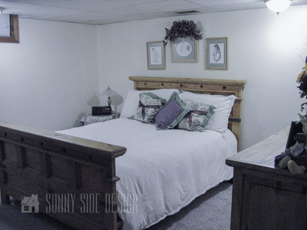 Before image of the bed, with white bedding, white walls with purple and green accent pillows.