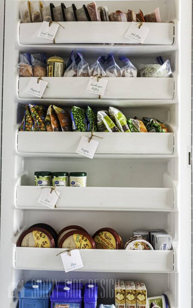 Freezer door organized with frozen food and each shelf is labeled.