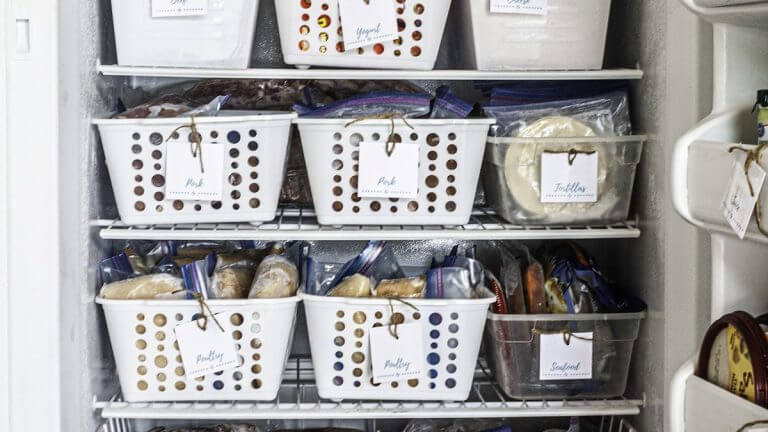 The best freezer organzation ideas, white plastic bins keep food organized and each bin is labeled.