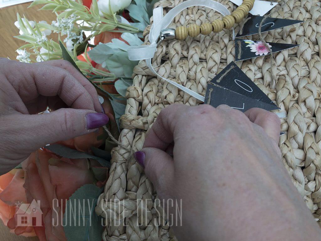 Attaching "hello spring" banner to basket full of flowers.