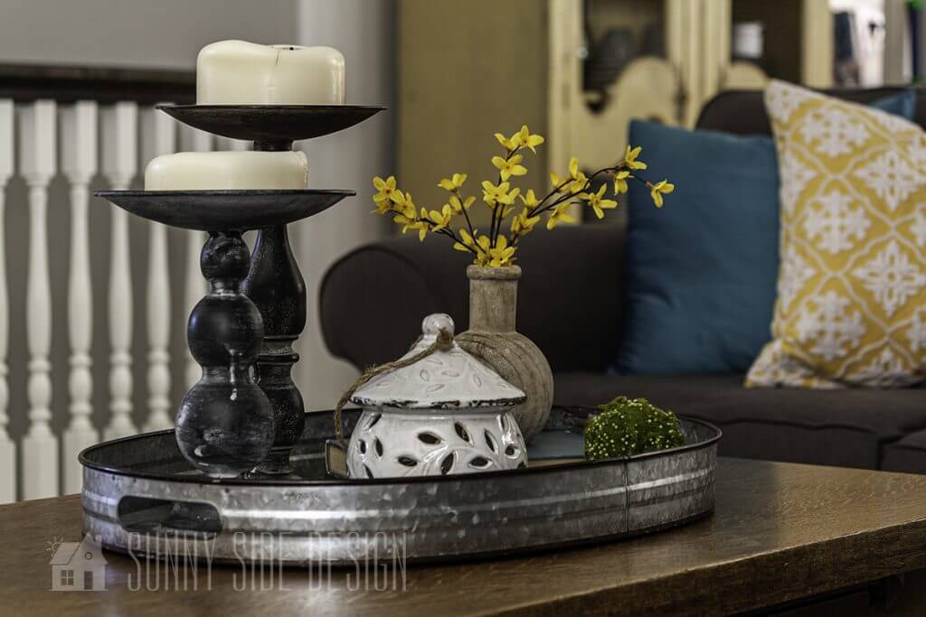 Spring Decorating ideas for the coffee table, forsythia in a natural wood vase, birdhouse, green moss balls and white candles.
