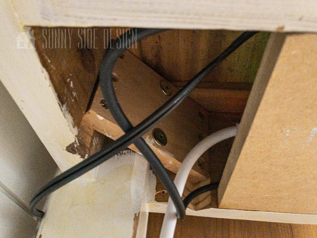 Wires and cables are routed around the desk leg to hide cords.