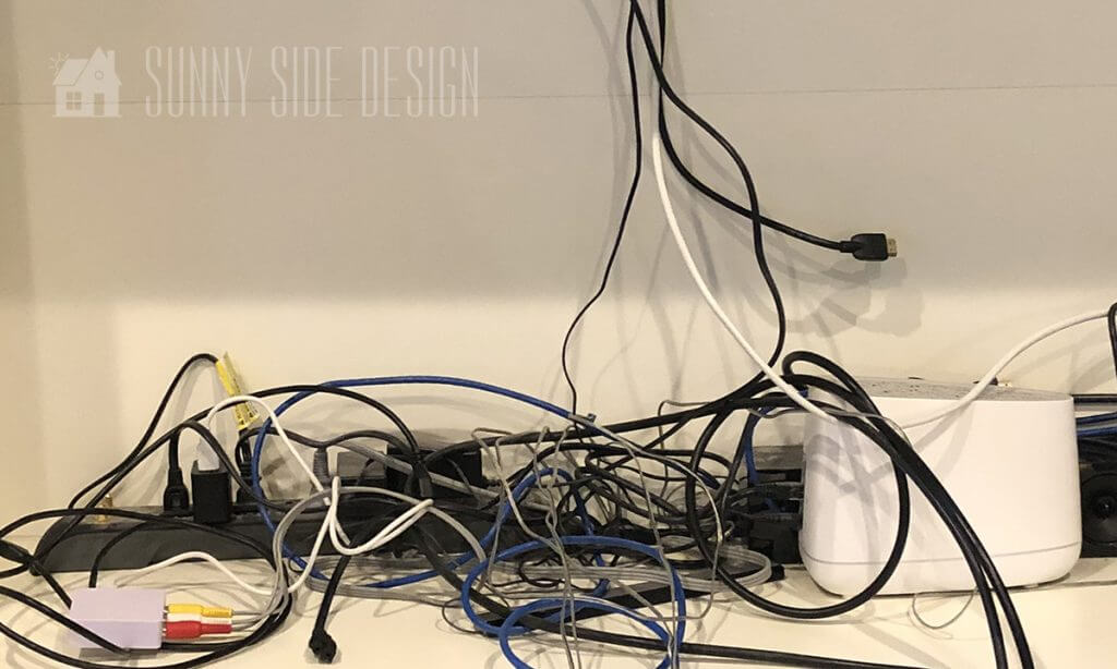 A tangled mess of cables and chords on floor under the desk before we implemented cable management.