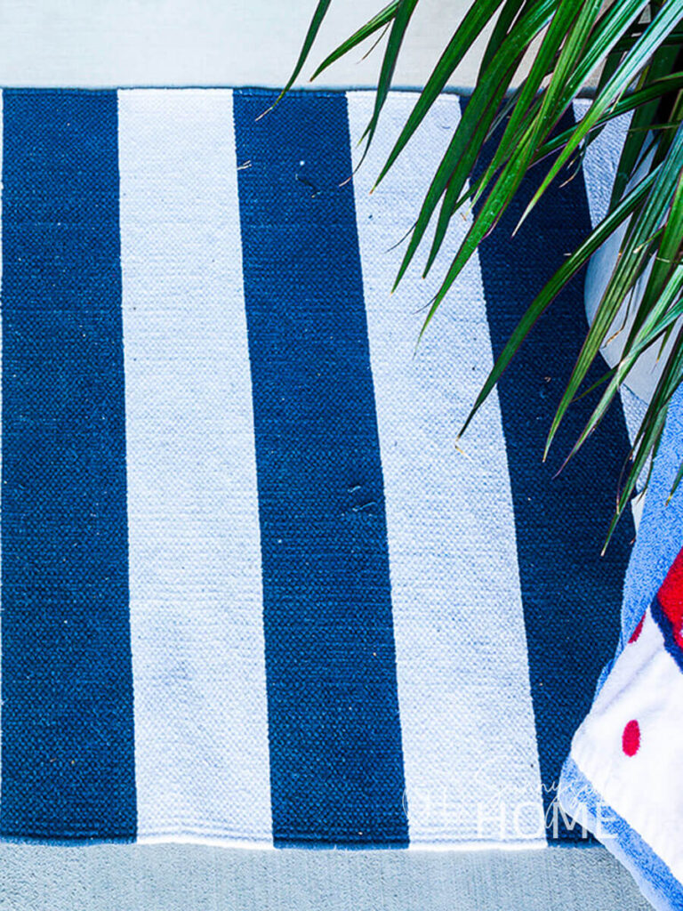 Front porch is decorated for the 4th of July with a blue and white striped rug.