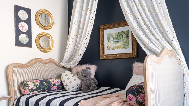 Upcycled Ideas: Beautiful upholstered French country daybed upcycled from a pair of twin beds. Styled with a bed crown, blue and white striped bedding with blush accent pillows.