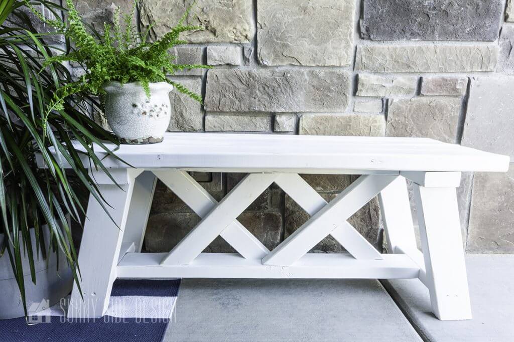 Simple white farmhouse style Bench on a small front porch, styled with plants.