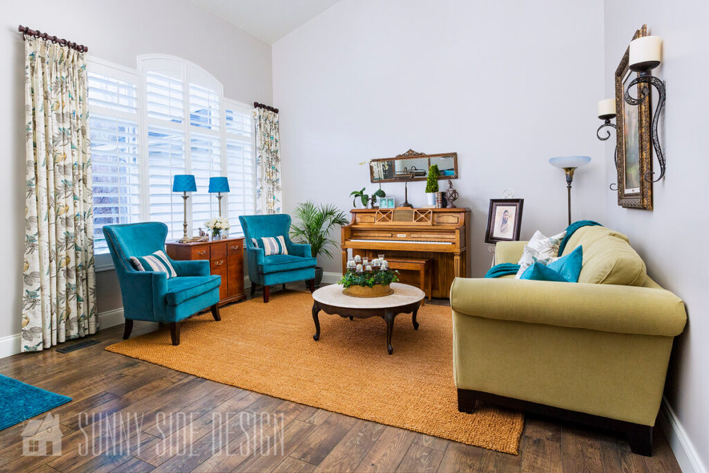 Living room with a large 8x10 sisal rug with a sage green sofa and teal blue accent chairs, marble and wood French coffee table, piano.
