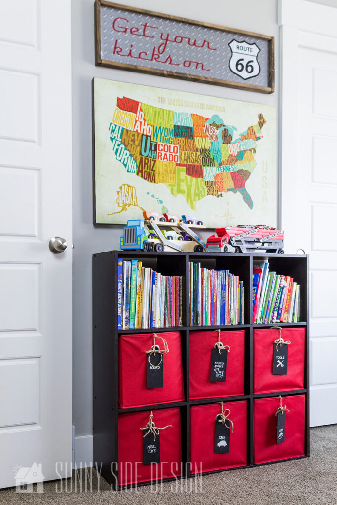 Little boys bedroom with wall art of United States, cubby organizer with books and labeled bins for toy storage
