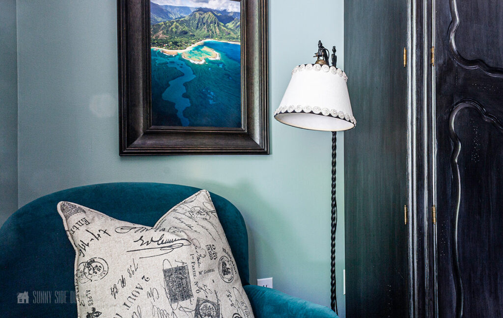 Teal accent chair with toss pillow and a vintage floor lamp with a white embellished shade.