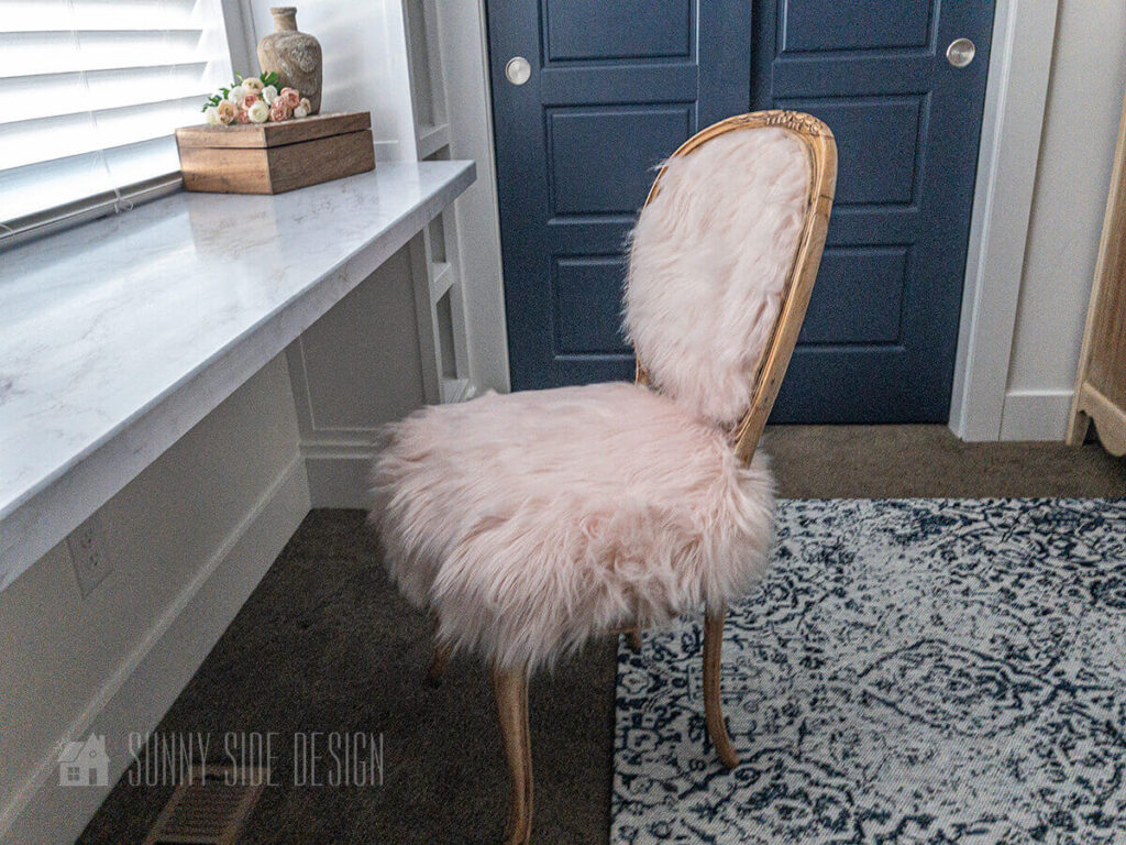 Vintage french country chair is brought to life with pink faux fur and a jute braid trim in this tween girls bedroom. Navy blue doors, desk and rug.
