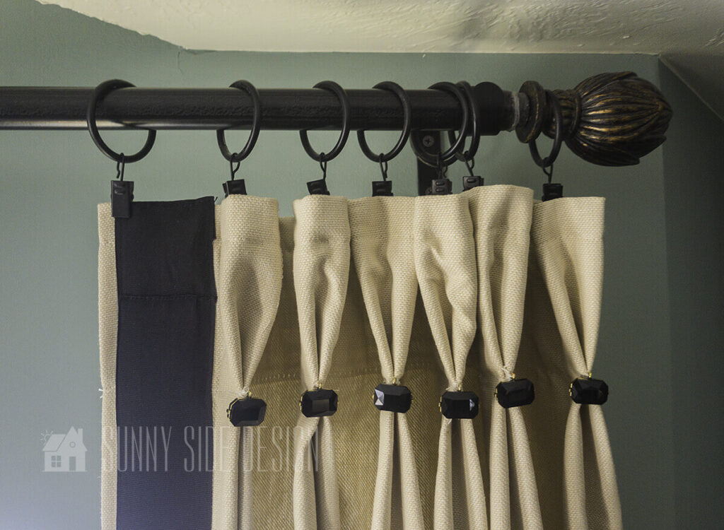 Ready made curtains are embellished with black grosgrain ribbon and a black braclet.