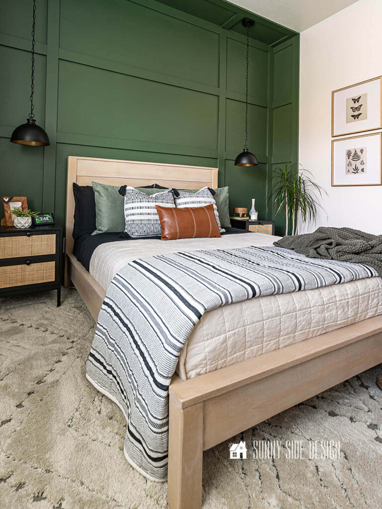 Easy board and batten wall painted green that extends around to the wall helps make this small bedroom feel larger. Modern platform bed with neutral bedding, black and cain nightstands, black pendants lights.