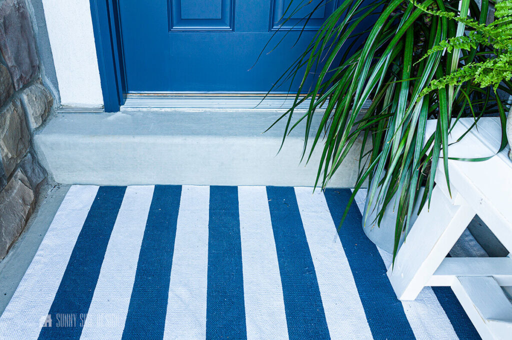 Navy blue paint freshens up this rug, also a navy blue front door, white bench and plant.