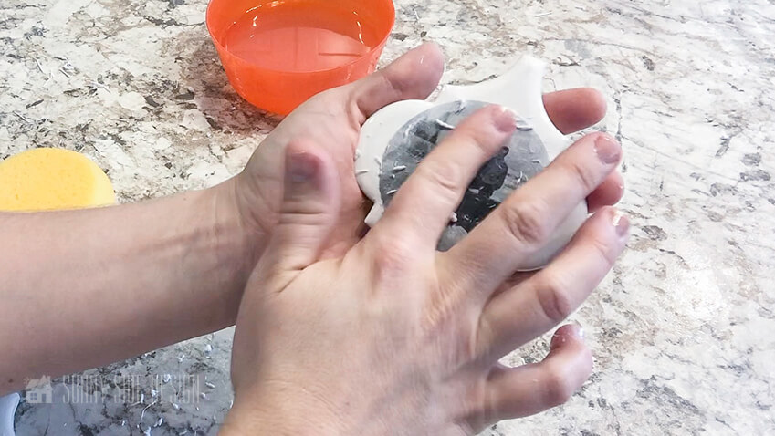 Woman's finger rubbing photo transfer as she transfers black and white photo to a white ceramic tile for a christmas ornament.