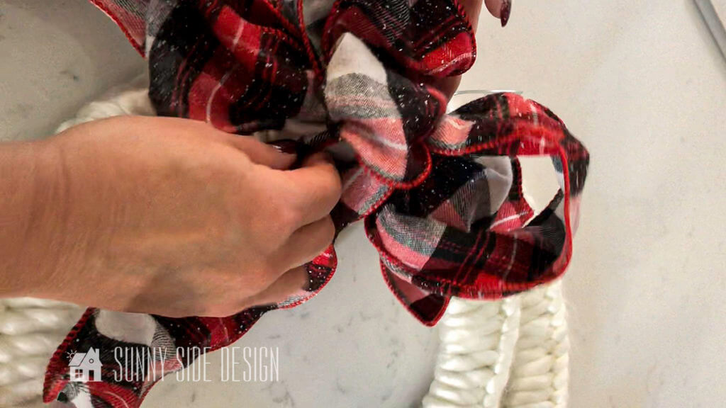 Attaching a red plaid bow to the Christmas Wreath