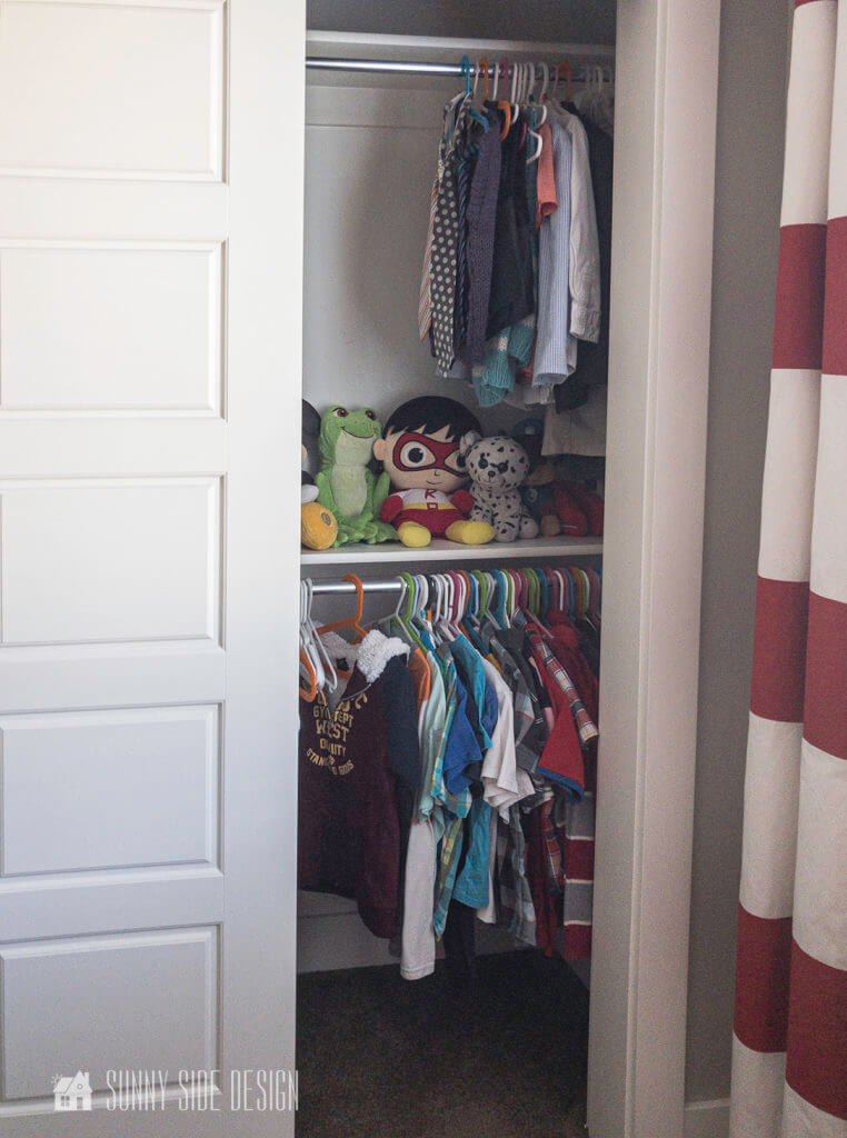 Organizing ideas for a kids closet. Clothes are on a lower rod for easy access and a few toys are stored on the shelf.