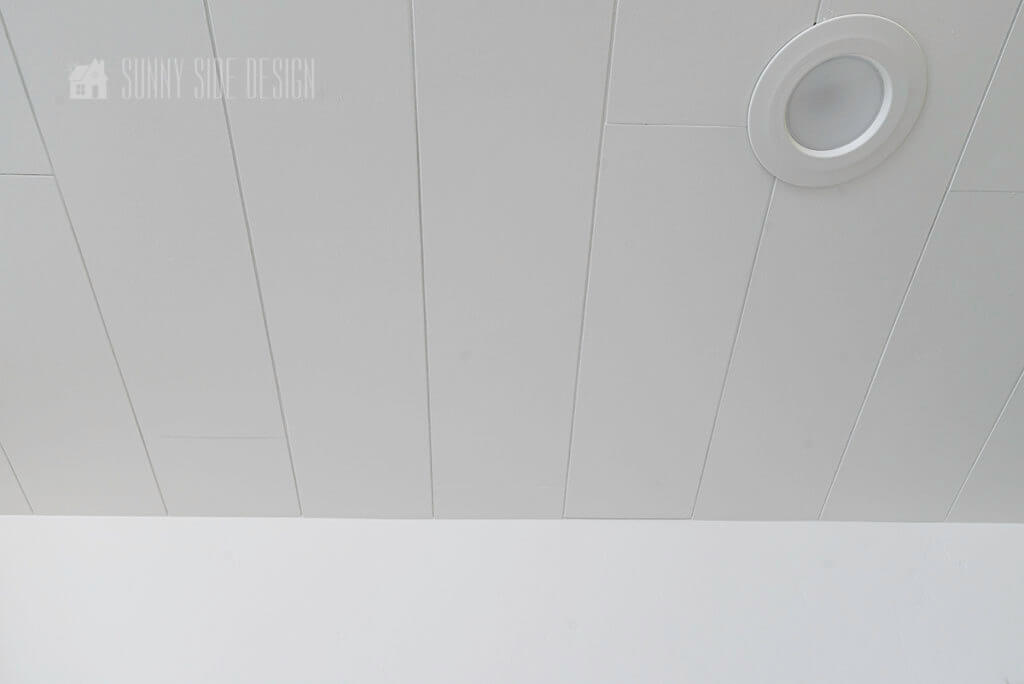 Completed shiplap ceiling painted white with can lights installed.