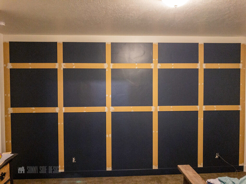 MDF board placed on a navy blue accent wall into a board and batten pattern.