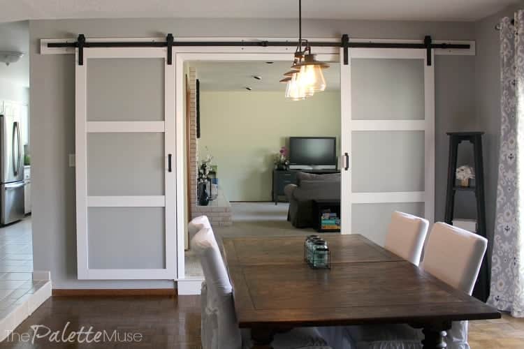 If you're not up to DIYing barn doors, find out everything you need to know to purchase them. White sliding barn doors painted white with glass inserts in a dining room.