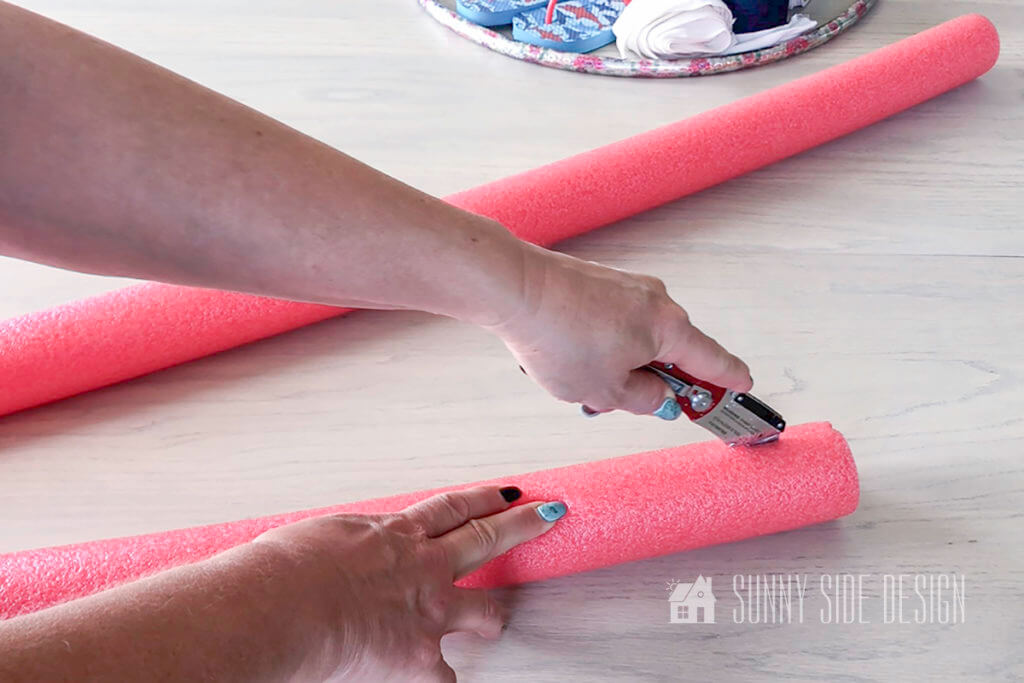 Woman making a slit in a pool noodle with a utility knife.