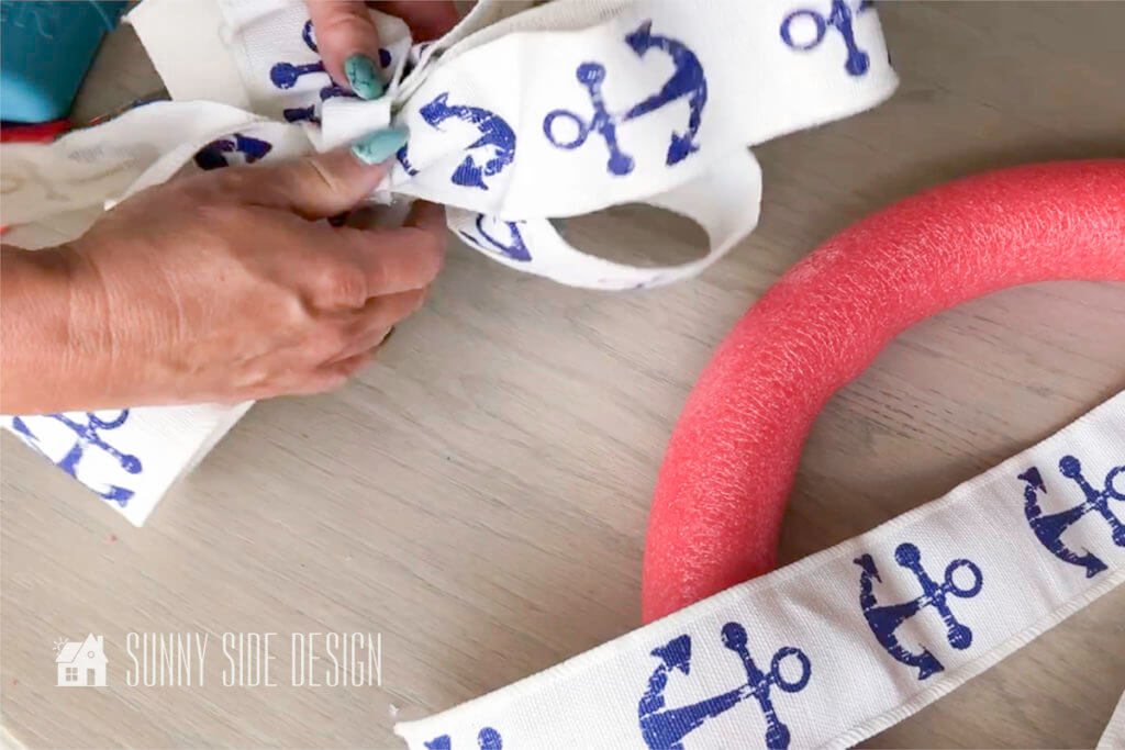 covering seam on the pool noodle wreath with nautical ribbon.