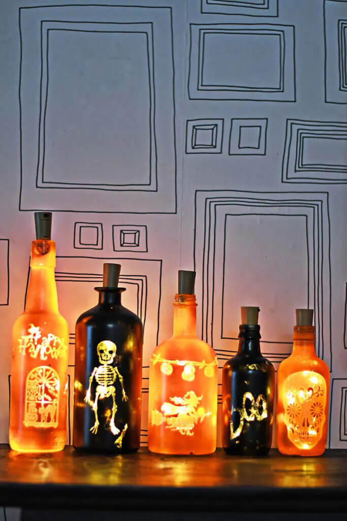 festive DIY Halloween decorations, spooky black and orange lit up bottles, decorated with halloween images.