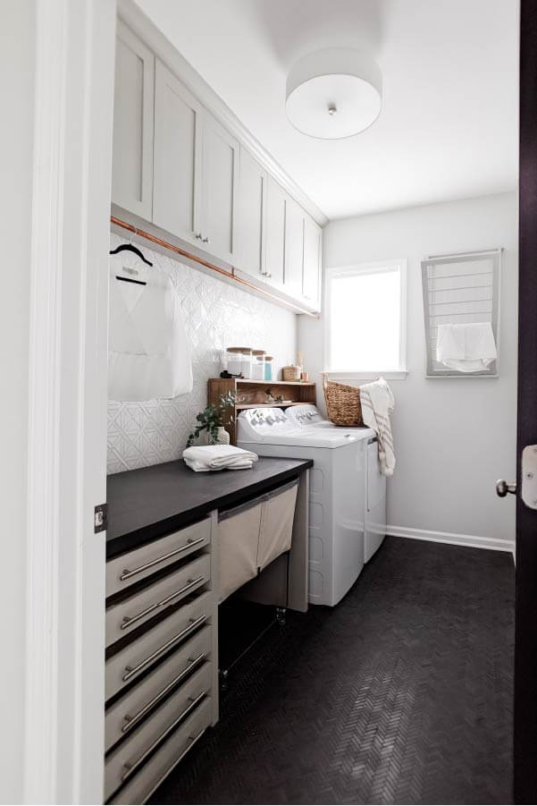 Organized white laundry room with ample storage. Pull out drying rack on wall and pull out drying drawers.