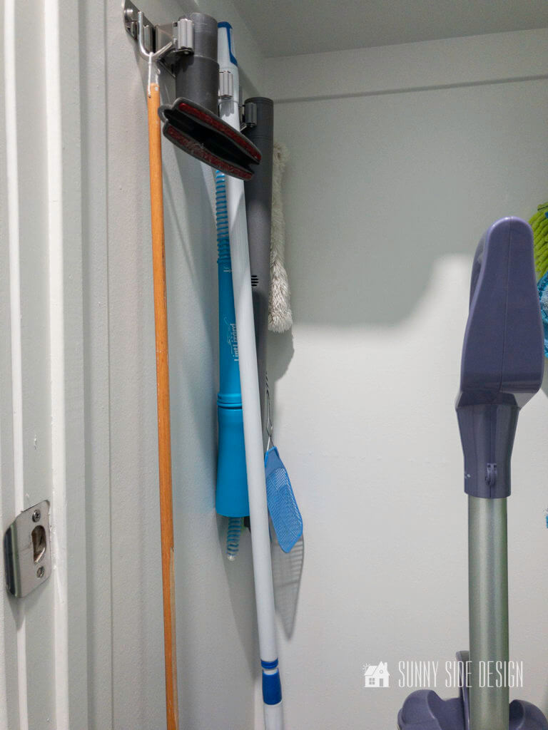 Hanging storage in a broom closet with cleaning tools and attachements for the vacuum cleaner.