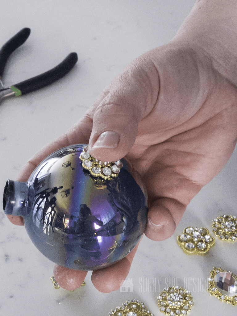 Embellish DIY glitter ornaments with rhinestone button.