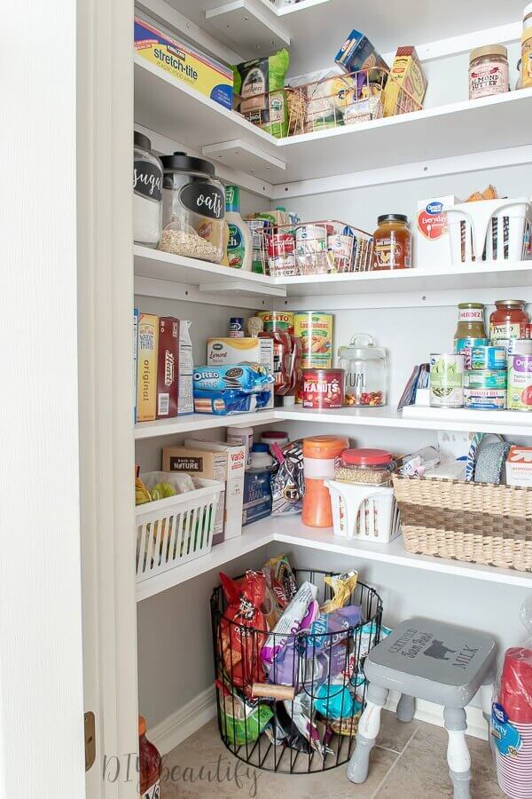 Pantry Organization Ideas - White painted shelves with light grey walls make this pantry look fresh and clean. Glass jars, baskets and plastic storage bins organize packaged food.