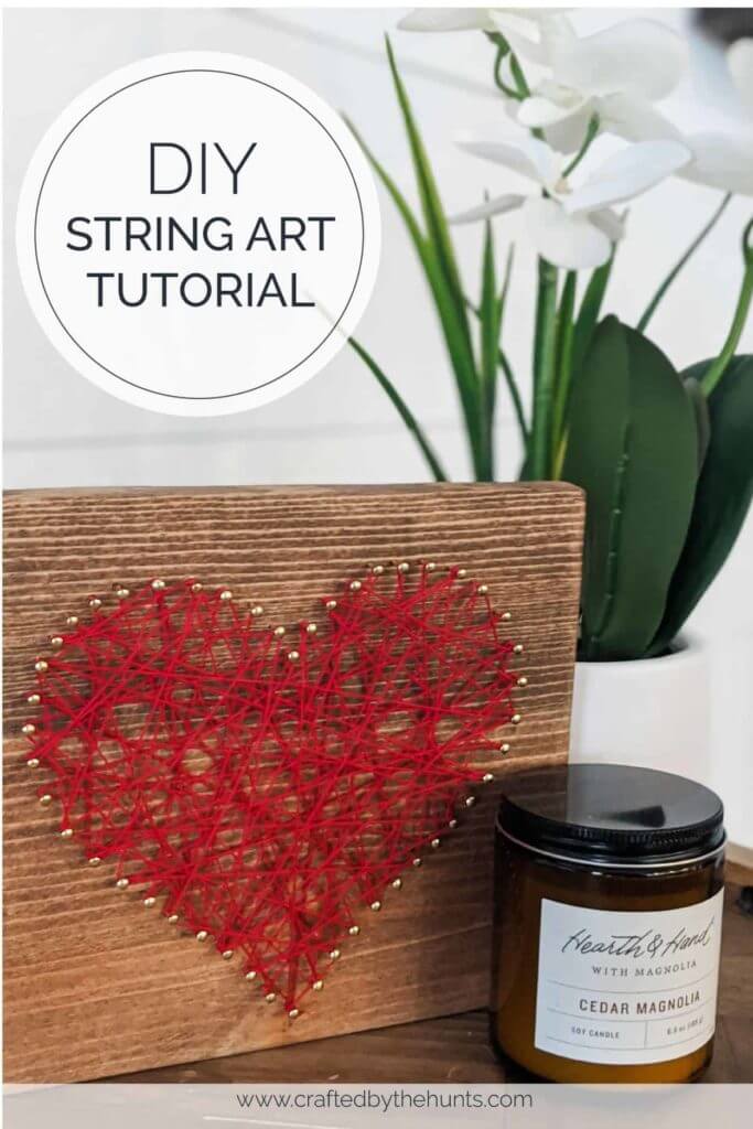 Heart string art on wood board, orchid in background and candle.
