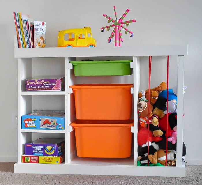 Toy organizing idea, DIY wood cabinet that stores, games on shelves, books and toys on top, pullout bins to organize more toys and a bungie cage area for stuffed animals.