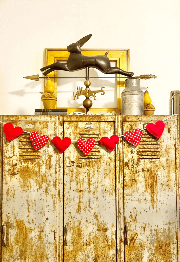 DIY Valentine's Day decorations, garland made with red felt hearts and red polka dot hearts hanging on rusty metal lockers.