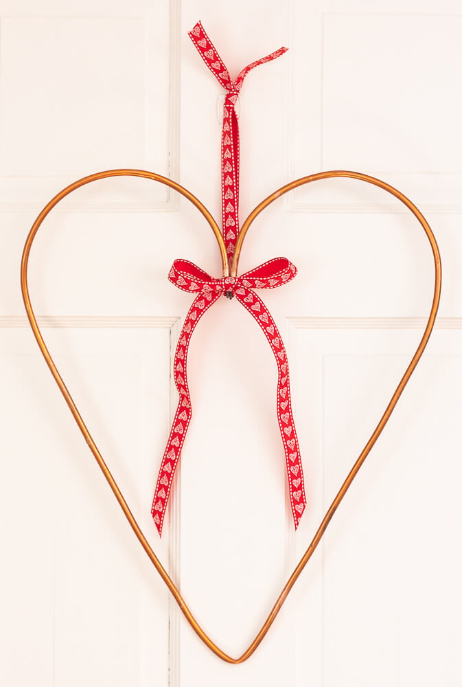 Simple minamalist copper wreath accented with red and white ribbon.