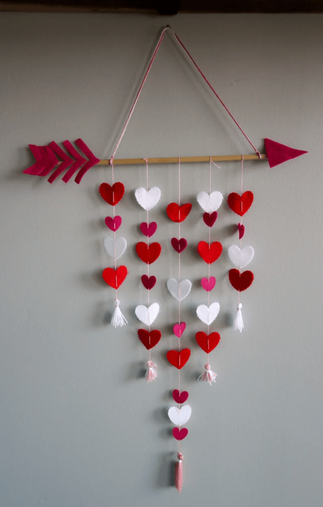 Wood and red arrow with red and white felt hearts hanging from cords.