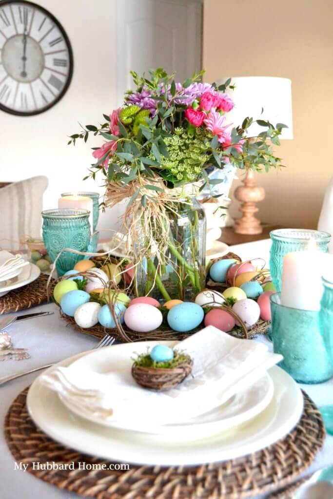 Egg wreath centerpiece with fresh flowers in a mason jar. Natural ratan charger with white plates and a small birds nest at each place setting.