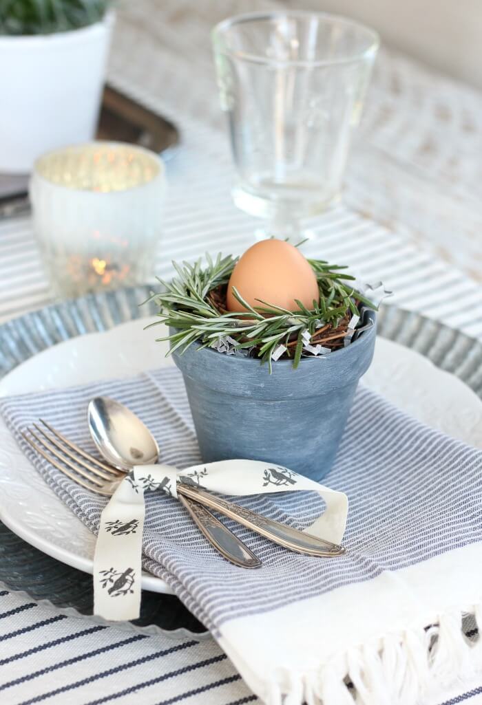 Easter Tablescape ideas, classic blue and white striped napkin, blue pot with rosemay nest and egg.