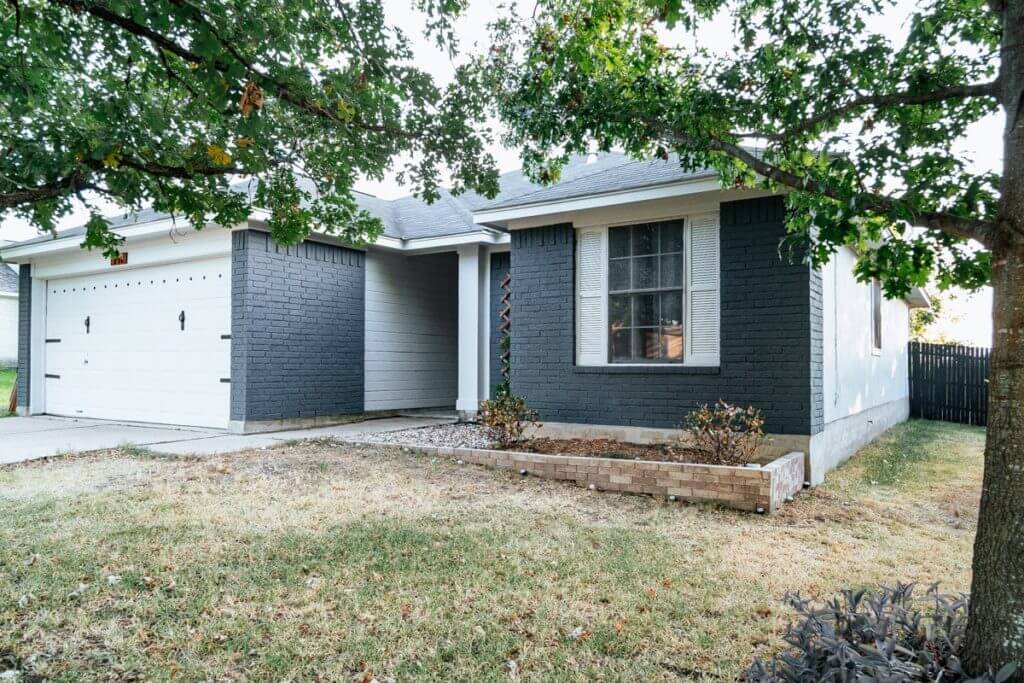 Curb appeal ideas, brick on this home is painted a dark grey and wood siding is painted white. Garage door is painted white with new carriage door hardware.