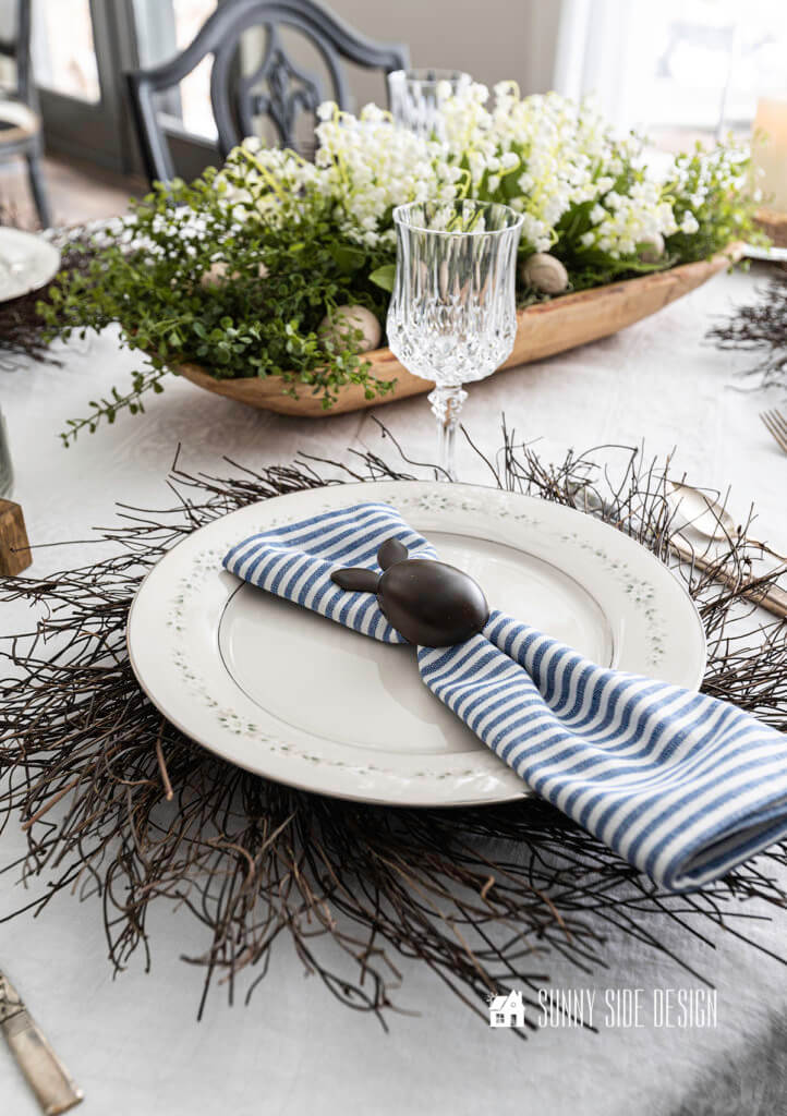 Easter place setting, with a floral white floral centerpiece in a rustic wooden dough bowl.