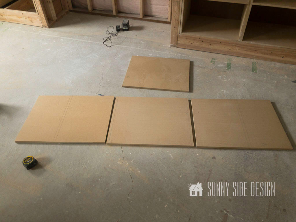 Four pieces of wood are placed on the floor showing the pieces necessary to make a cabinet.
