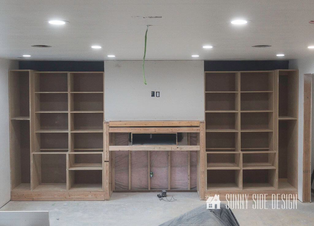 Cabinet carcass and book shelves are placed into position along the built in entertainment center wall.