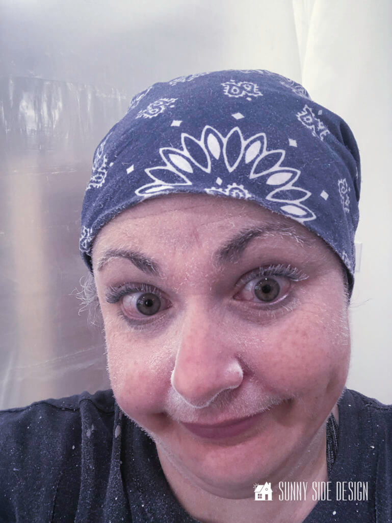 Woman's face covered with paint dust, wearing a blue bandana and blue t-shirt.