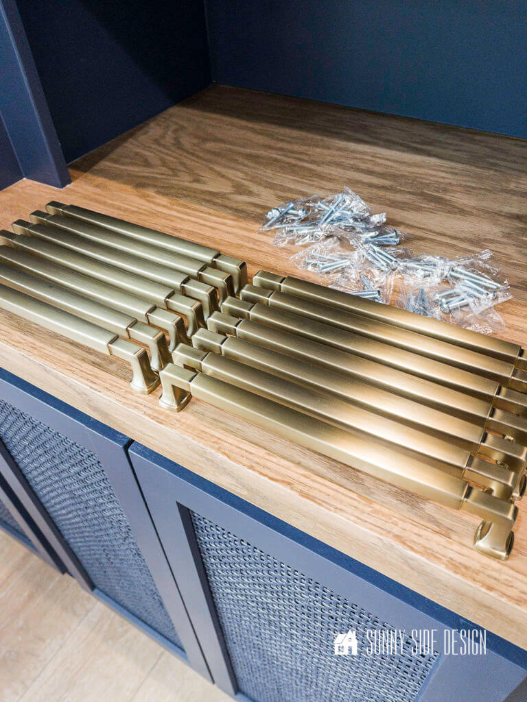 Champagne gold long cabinet pulls setting on the top of the oak countertop on the built in entertainment center.
