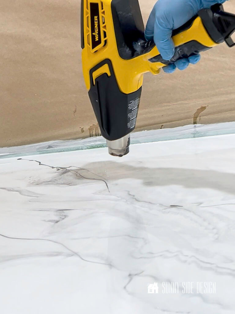A heat fun is used to meld the black and white color veining with a DIY epoxy countertop.