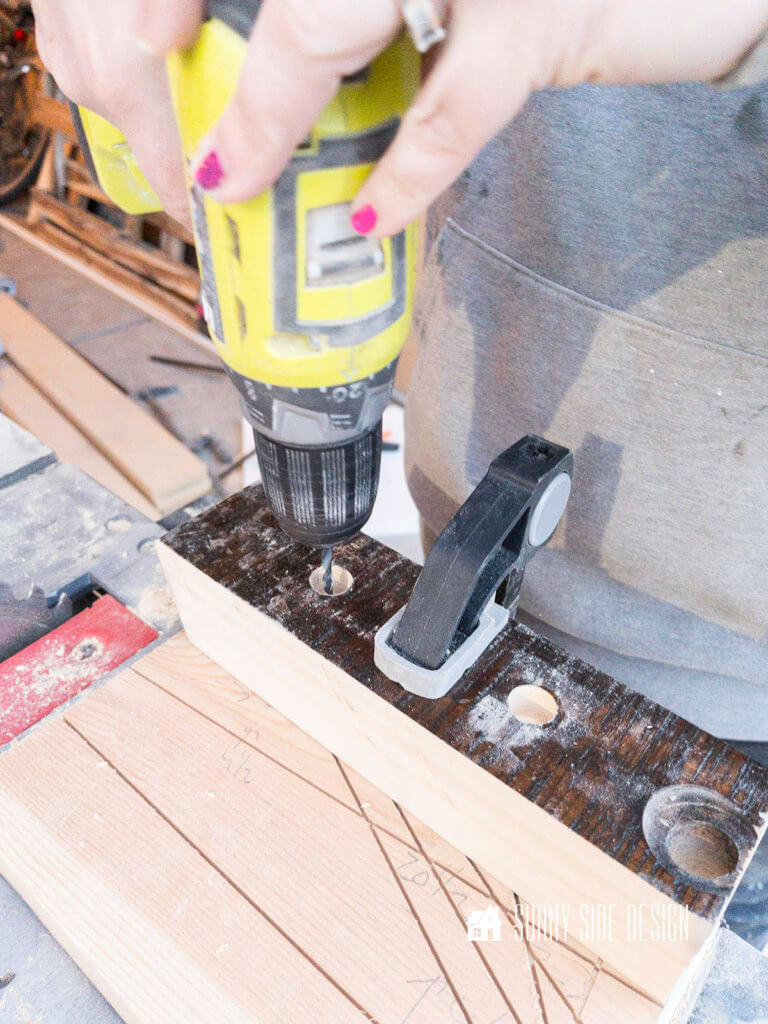Drilling a hole in a piece of wood for the leg of the sofa table.