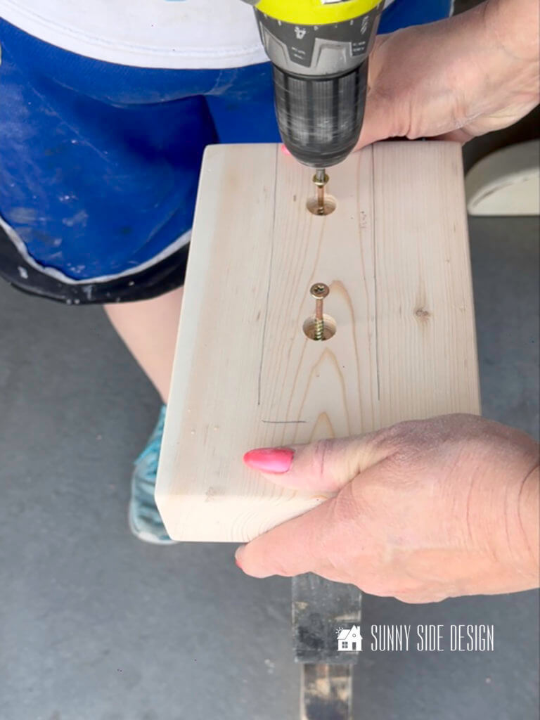 Woman with drill inserts screws into wood for the DIY sofa table leg.