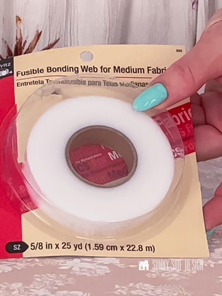 Woman's hand holding a package of fusible bonding web.